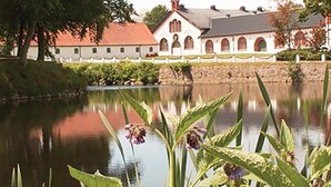 A serene lakeside view with a historic building featuring arched windows and a red roof. - Gorgeous home in Tomelilla with WiFi (Tomelilla)
