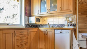 A kitchen with wooden cabinets, a Bosch dishwasher, a microwave, and a coffee maker. - Beach front home in Os (Os)