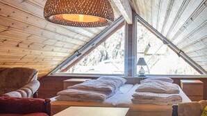 A cozy room with a sloped ceiling, a large window, and a hanging light fixture. - Beach front home in Os (Os)
