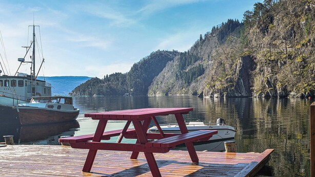 A wooden dock with a picnic table, boats, and a forested hillside. - Beach front home in Os (Os)