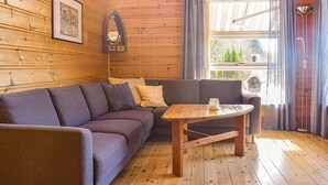 A cozy room with a wooden interior, a sofa, a small table, and a window with curtains. - Beach front home in Os (Os)