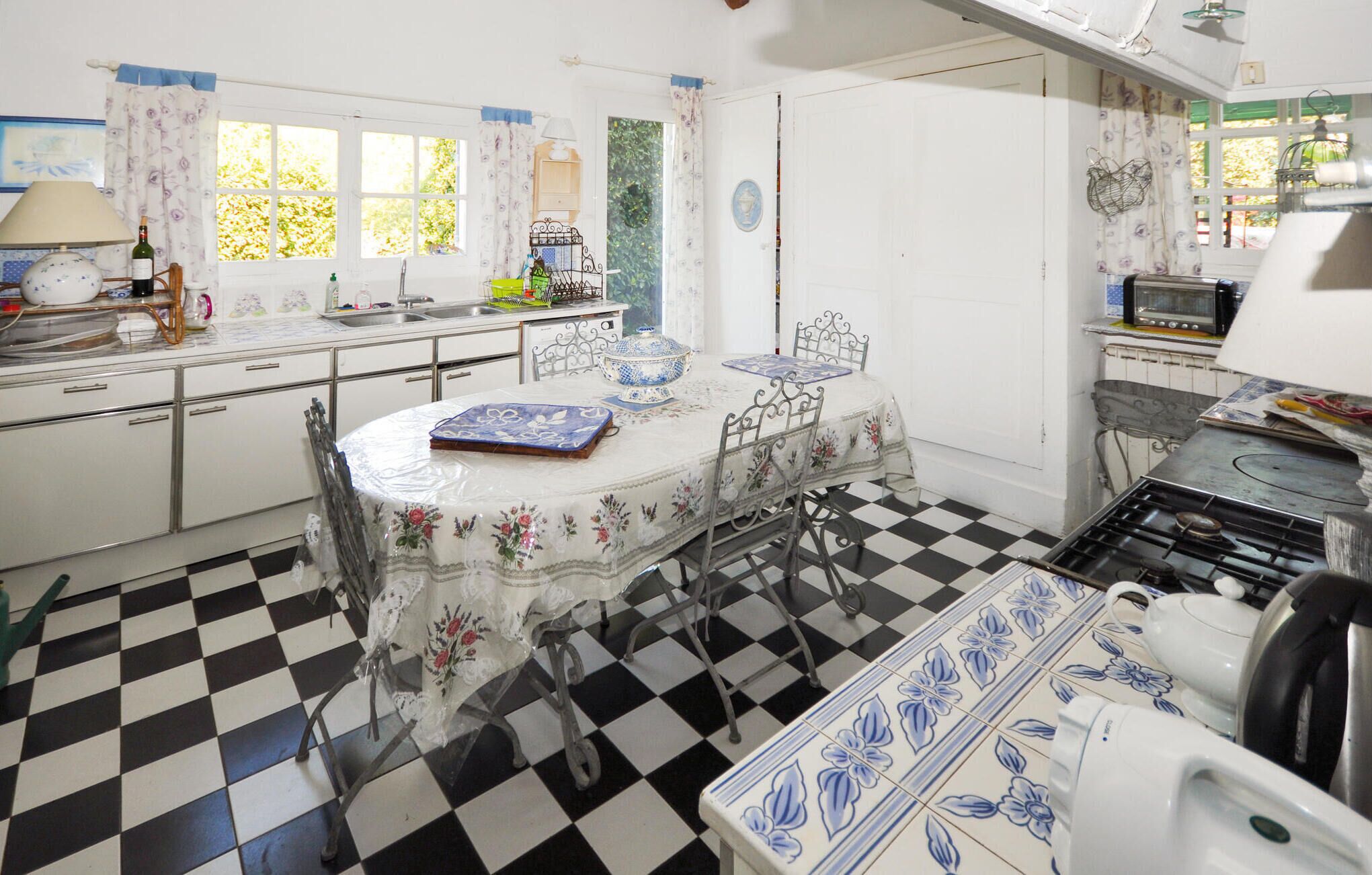 Une cuisine avec un carrelage à motifs, une table à manger avec des chaises, une cuisinière et divers appareils de cuisine.