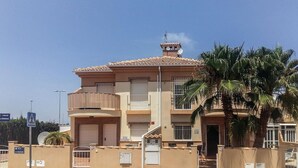 A multi-story residential building with a tiled roof, balconies, and a satellite dish.