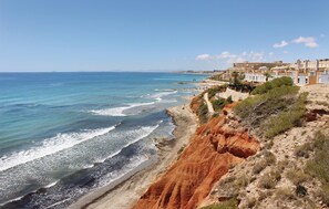 A coastal town with buildings along the cliffside, a beach with waves, and a clear sky. - Amazing home in Orihuela Costa with WiFi (Orihuela Costa)