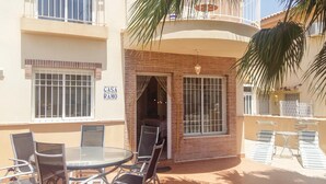 A patio with a glass table and chairs, a sign reading "CASA RAMO", and a brick wall.