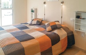 A bedroom with a large bed, two bedside lamps, a white wardrobe, and a small shelf with decorative items. - Amazing home in Orihuela Costa with WiFi (Orihuela Costa)