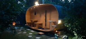 A wooden cylindrical structure with a small window, a table, and chairs inside.