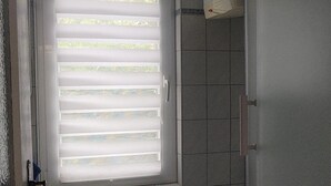 Et badeværelse med vask, toilet og vindue med skodder.