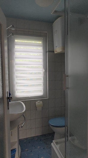 A bathroom with a sink, toilet, and window with blinds. - Holiday home Idyll, Germany (Blankensee)