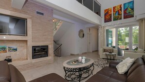 A spacious living area with a fireplace, comfortable seating, and artwork on the walls.