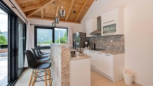 A modern kitchen with a stone island, stainless steel appliances, and a view of the outdoors.