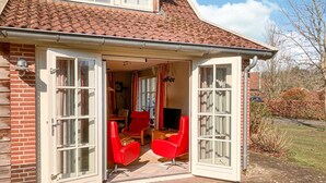 A house with a patio, red chairs, and a TV. - Buitengoed Het Lageveld - 65 (Hoge Hexel)