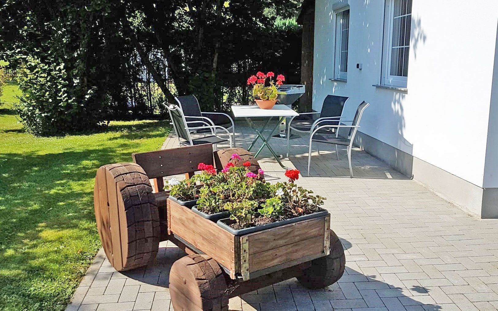 A wooden cart with flowers on a paved patio.