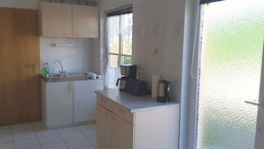 A compact kitchen with a sink, stove, and coffee maker.