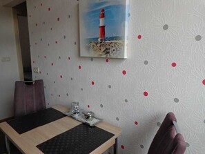 Un coin repas comprenant une table, des chaises et un tableau représentant un phare.