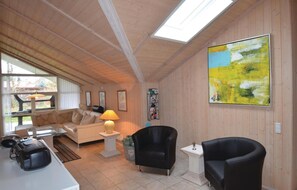 Relax in a spacious room with a high ceiling, featuring a comfortable sofa set, a leather armchair, and a small table with a lamp.