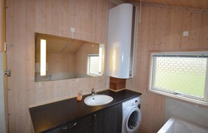 Enjoy a warm and inviting bathroom with a washing machine, sink, and large mirror.