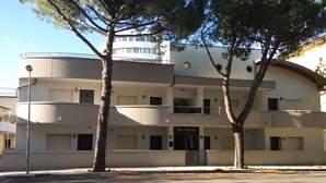 A multi-story building with balconies, a storefront labeled "Villa Nodari," and trees in front. - Holiday apartment with balcony and air conditioning (Lignano)