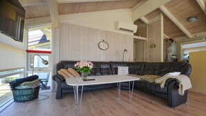 Un salon chaleureux avec un canapé en cuir foncé, une table basse blanche et une horloge au mur.