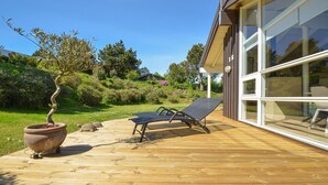 Une terrasse en bois avec deux chaises longues et une plante en pot.