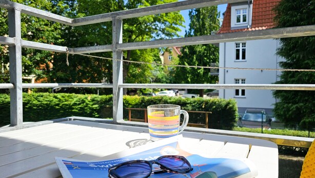 Una mesa con una revista, una taza a rayas y un par de gafas.