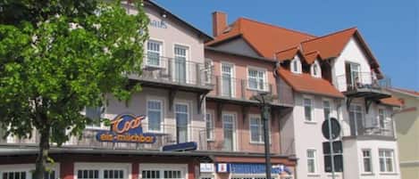 Un edificio de varios pisos, con balcones y un letrero de una heladería.