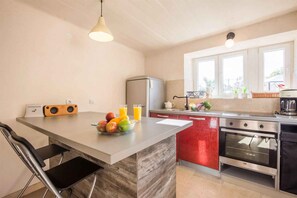 A modern kitchen with a central island, a built-in oven, and a refrigerator.
