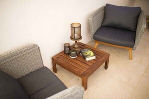 A wooden coffee table with two wicker chairs, a lamp, and a book.