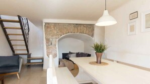 A modern living space with a staircase, a bench, a potted plant, and a stone wall. - Holiday home with terrace and barbecue (Polje/Krk)