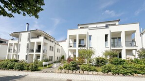 A modern apartment building with multiple balconies and a paved entrance area. - A: Villa Antje Whg. 12 with balcony - Villa Antje Whg. 12 with balcony (Göhren)