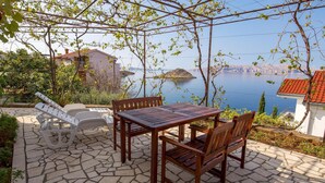 Un patio al aire libre con una mesa y sillas, con vistas a un lago y montañas al fondo.