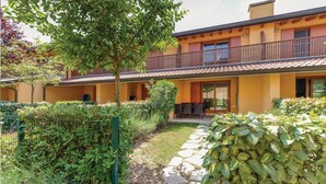 A two-story building with a balcony, stone pathway, and well-maintained garden.