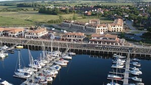 Ein Yachthafen mit mehreren vertäuten Booten, einer Uferpromenade und Gebäuden im traditionellen Stil.