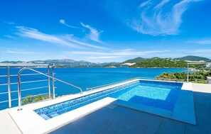 A pool with a view of the sea and mountains.