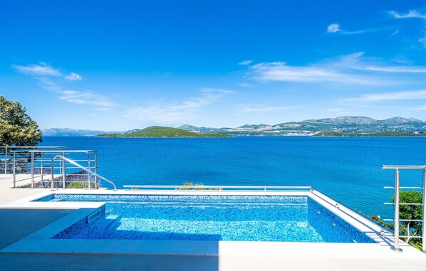 A swimming pool with a view of a large body of water and distant hills.