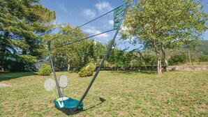 Uma quadra de badminton com rede, duas raquetes de badminton e um suporte para peteca.