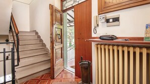 Um corredor com escada de madeira, um radiador e um telefone.