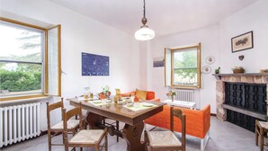 Uma sala de jantar com mesa de madeira, cadeiras, lareira e um quadro negro com anotações.