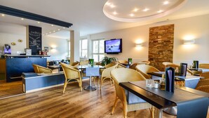 Een moderne hotel lobby met rieten meubels, een bar, een televisie en een accentmuur van steen.