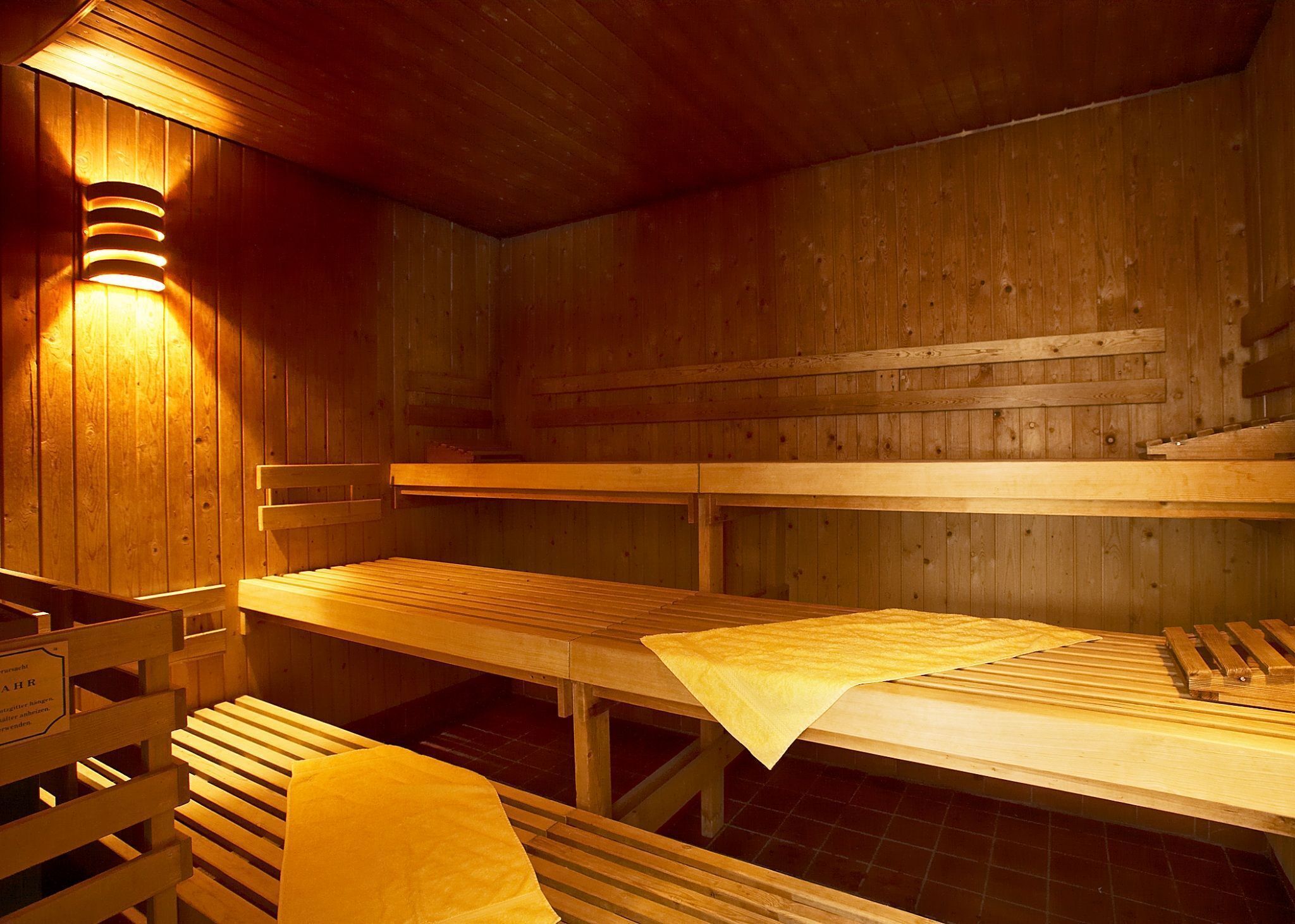 Un sauna avec des bancs en bois et des coussins recouverts de serviettes.