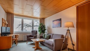 Een ingerichte kamer met een televisie, een bank, een tafel, een lamp en een statief.