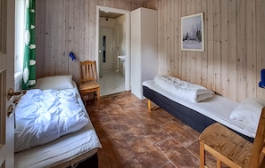 A room with two beds, a bench, a chair, and a door leading to another room. - Stunning home in Dølemo with sauna (Dølemo)