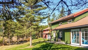 Une rangée de maisons vertes aux toits rouges, entourées d’arbres et d’une zone herbeuse.