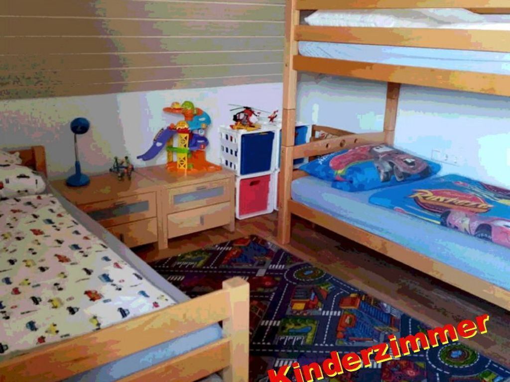 Une chambre d’enfant avec des lits superposés, un bureau et un espace de jeux coloré.