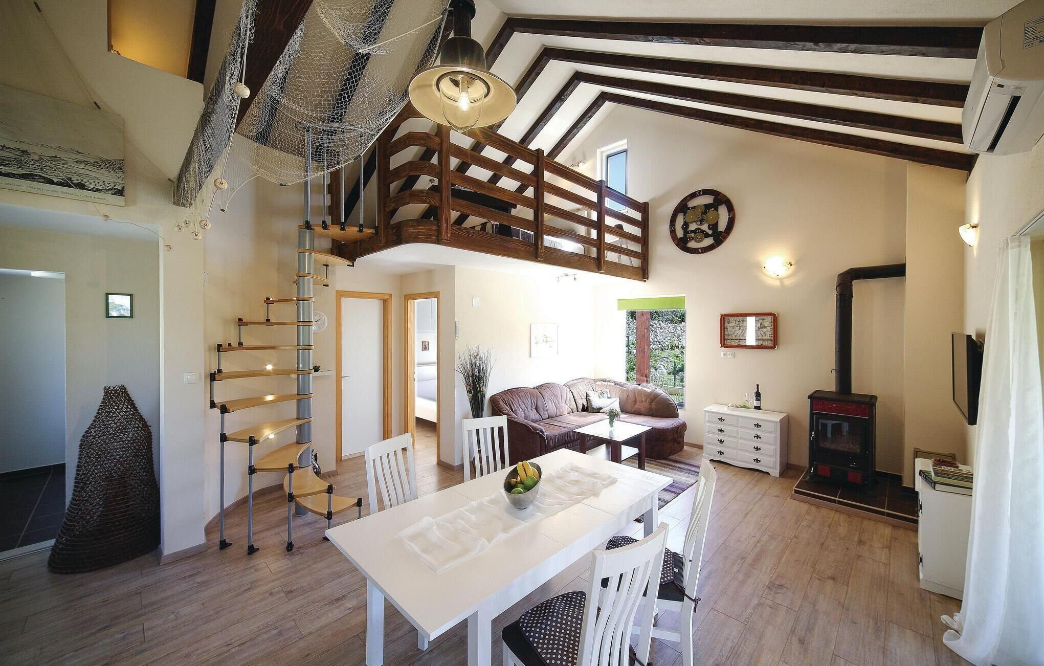 Un vaste espace de vie doté d’un haut plafond, d’un escalier en bois, d’une table à manger avec des chaises, d’un canapé et d’une cheminée.