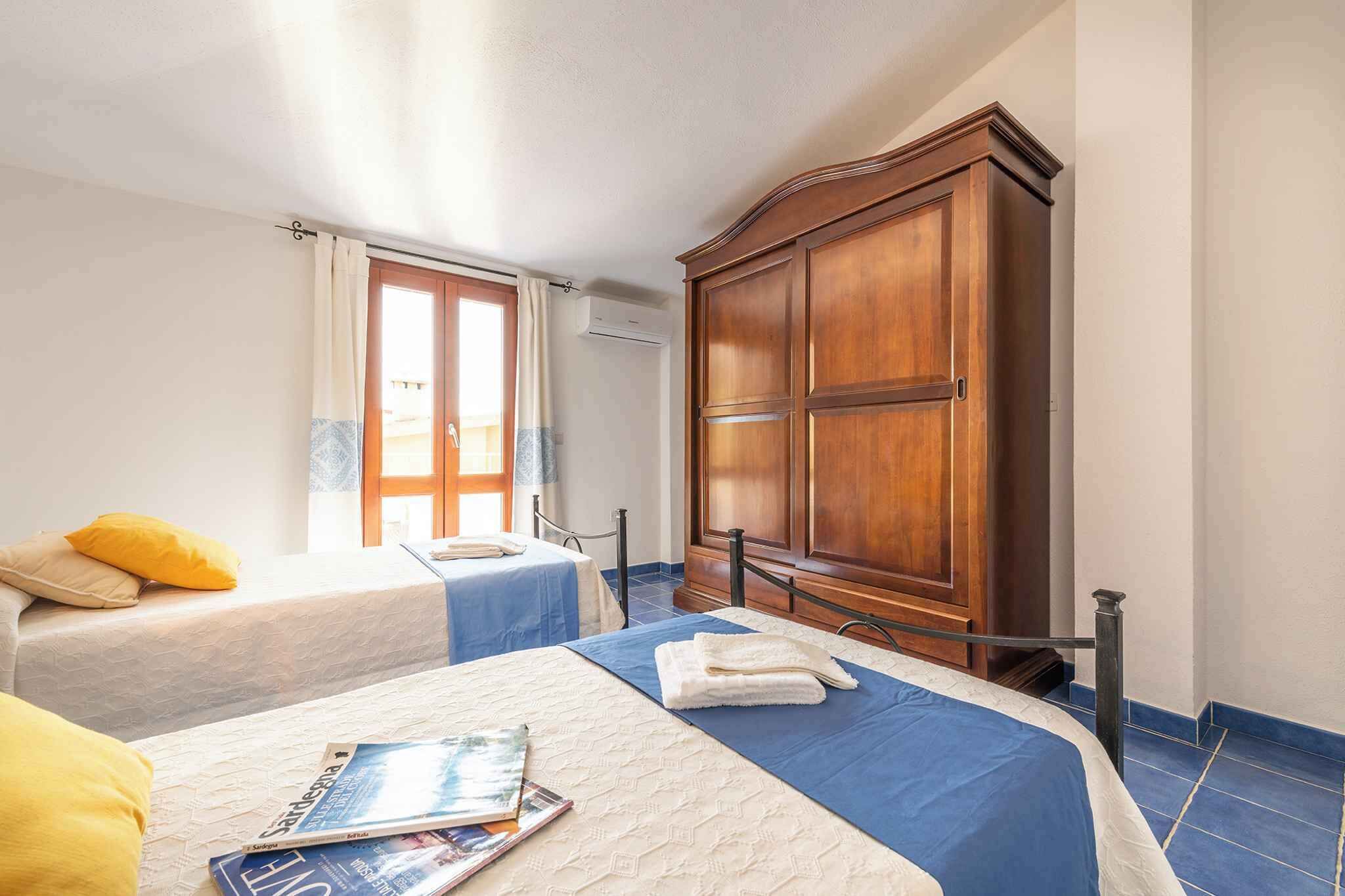 A hotel room with two beds, a wooden wardrobe, and a window with curtains.