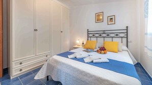 A bedroom with a bed, a wardrobe, a nightstand, and two framed pictures on the wall. - Holiday apartment mit Meerblick (Cala Gonone)