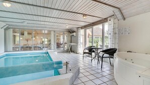 A pool area with a hot tub, tiled flooring, and large windows offering views of the outdoors. - Nice home in Blåvand with sauna (Blåvand)