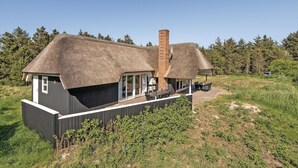 A modern house with a thatched roof, a brick chimney, and a covered outdoor seating area. - Nice home in Blåvand with sauna (Blåvand)