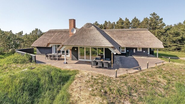 A thatched-roof house with a patio, surrounded by trees. - Nice home in Blåvand with sauna (Blåvand)
